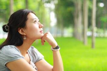 Woman outdoors looking up and thinking about starting therapy.